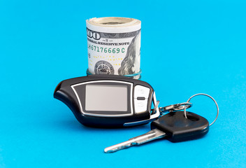 Car keys with money on a blue background.