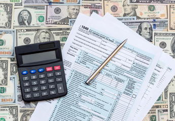 Obraz premium 1040 tax form with calculator on the dollars background.