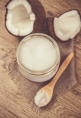Coconut oil and fresh coconuts on a wooden table.