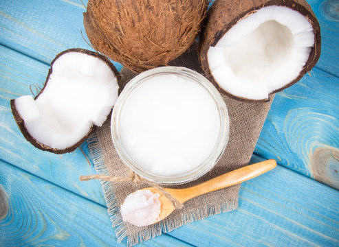 Coconut oil and fresh coconuts on a wooden table.