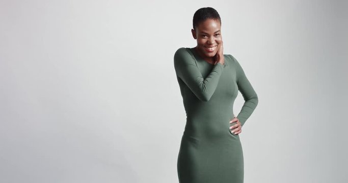 Attractive athletic female black model in a tight fitting jersey longsleeve greyish green dress on white background