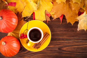 Autumn horizontal banner with yellow, red leaves, pumpkins, cup of coffee and guelder rose on brown wooden background. Concept for thanksgiving day, halloween, seasonal sales card, flyer