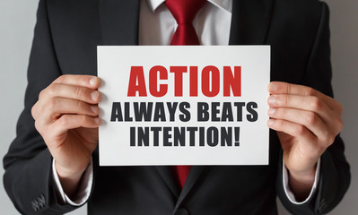Obraz premium Businessman holding a card with text Action Always Beats Intention