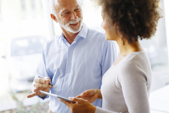 Senior Businessman And Young African American Businesswoman With Tablet