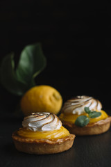 Lemon pie on the table with citrus fruits. Traditional french sweet pastry tart. Delicious, appetizing, homemade dessert with lemon cream. Copy space, closeup. Selective focus. Toned