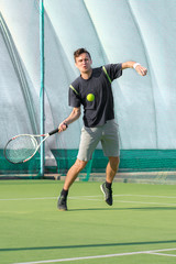 Tennis player playing a game of tennis on a court. The ball is suspended in the air.