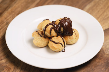 profiteroles covered with black chocolate on plate closeup