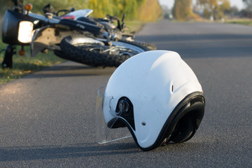 Photo of helmet and motorcycle on the road, the concept of road accidents - obrazy, fototapety, plakaty