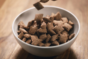 chcolate cereal pillow falling into white bowl on table