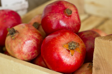 Fototapeta na wymiar Ripe red pomegranates in a wooden box on brown burlap