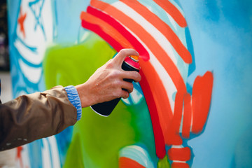 Artist graffiti with a balloon paint in his hands draws on the wall