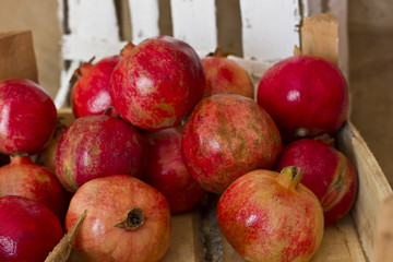 Ripe red pomegranates in a wooden box on brown burlap