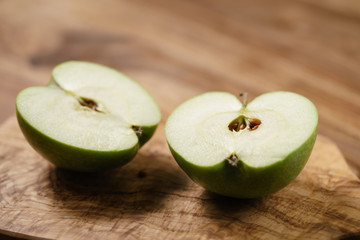 halves of green apple on wood table
