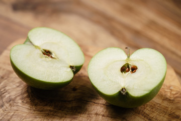 halves of green apple on wood table