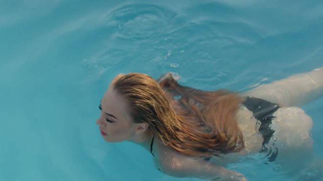 Seductive blonde with long hair swim in pool
