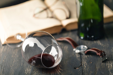 Red wine glass and old open book on wooden table