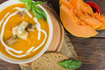Pumpkin and carrot soup with cream and parsley on dark wooden background Top view