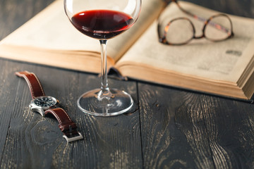 Still life with red wine and old books on the old wooden table in retro style