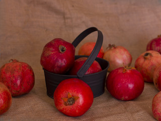 Ripe red pomegranates in a metal black bowl on a brown burlap