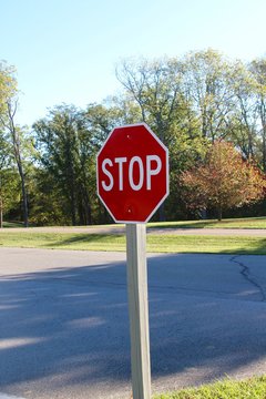 The stop sign on the wood post in the park.