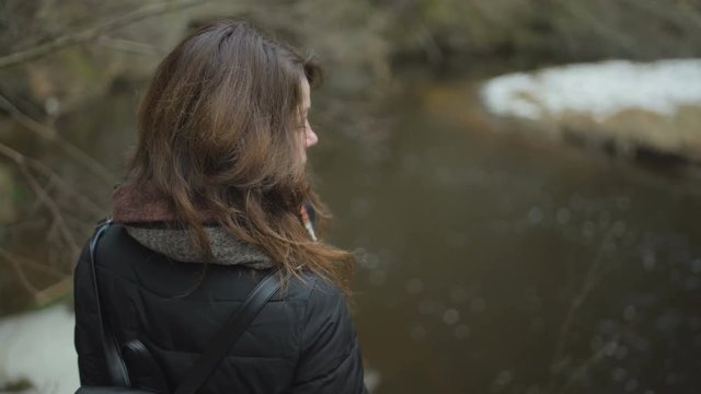 Woman standing by the river in a cold weather