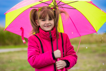 Happy child girl laughing with an umbrella in the rain in autumn day
