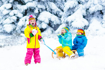Kids on sleigh ride. Children sledding. Winter snow fun.