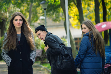 Fototapeta premium Disloyal man walking with girlfriend and looking amazed at another seductive girl