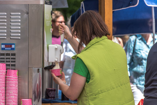 Female Hand Holding Cup With Soft Frozen Yogurt Or Ice Cream From Machine.