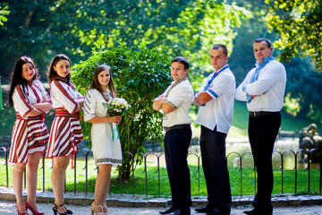 Obraz premium Newlyweds, groomsmen and bridesmaids pose together in a summer park