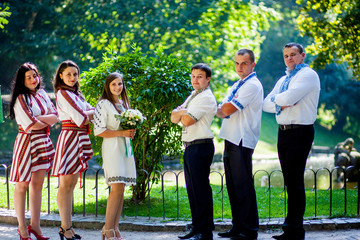 Newlyweds, groomsmen and bridesmaids pose together in a summer park