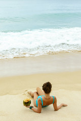 Fototapeta na wymiar Woman with a coconut on the beach