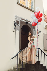 Woman in beautiful dress with a lot of colorful balloons