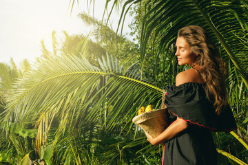 Happy young woman with a basket full of exotic fruits