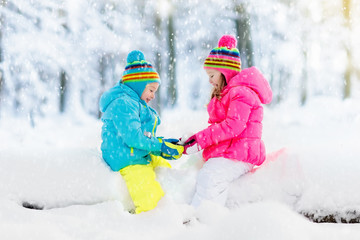 Kids playing in snow. Children play outdoors in winter snowfall.