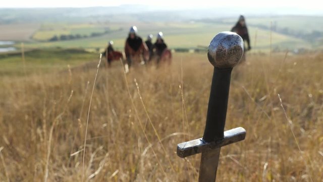 Sword sticking in the ground on the backgrond of going vikings