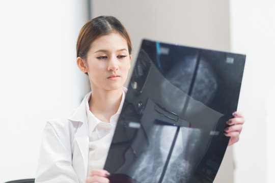  Thoughtful female doctor looking at the Mammogram film image.