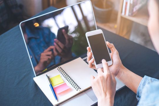 Woman hand using a white mobile phone on a blank screen.