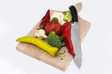 peppers, carfiol and broccoli with a knife on a wooden board isolated on white