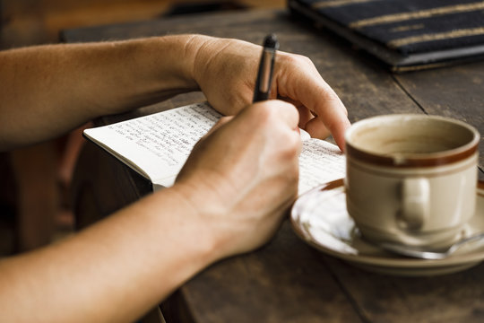 Frau schreibt Tagebuch - mit Kaffee