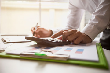 Business man working at office with calculator and documents on his desk