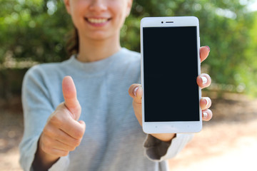 A smiling woman holding cell phones and making like with the hand