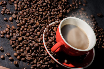 Hot coffee in red cup and coffee beans are the background.