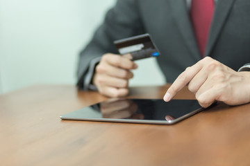 Businessman using tablet and credit card for online shopping or banking.