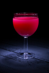 red cocktail in a glass on a black background