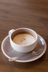 Coffee in a cup on a wooden table with a spoon