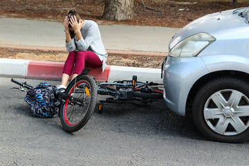 Fototapeta na wymiar A woman holding her head near a traffic accident between electric bicycle and car