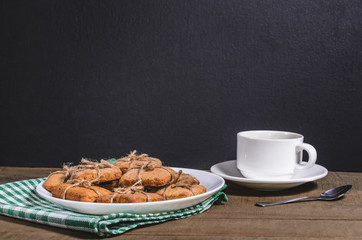 Black coffee in a white cup on a green napkin and homemade cookies.