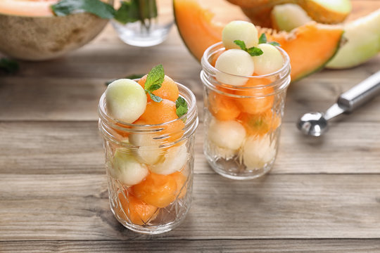 Jars with fresh melon balls on table