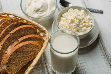 Rural dairy farm products on a wooden table: milk in a glass, cottage cheese, sour cream